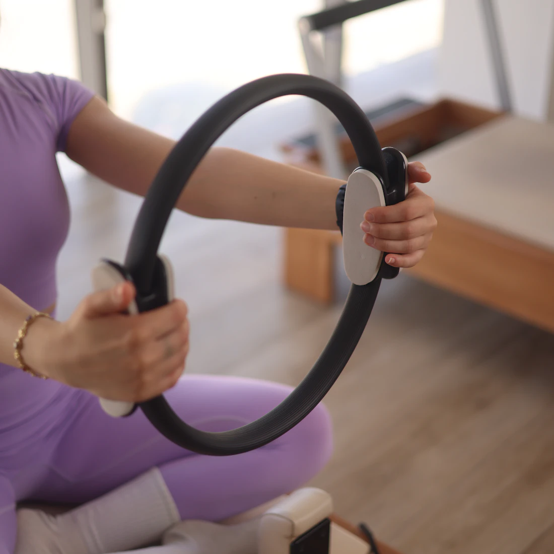 Mãos segurando um círculo de pilates durante exercício